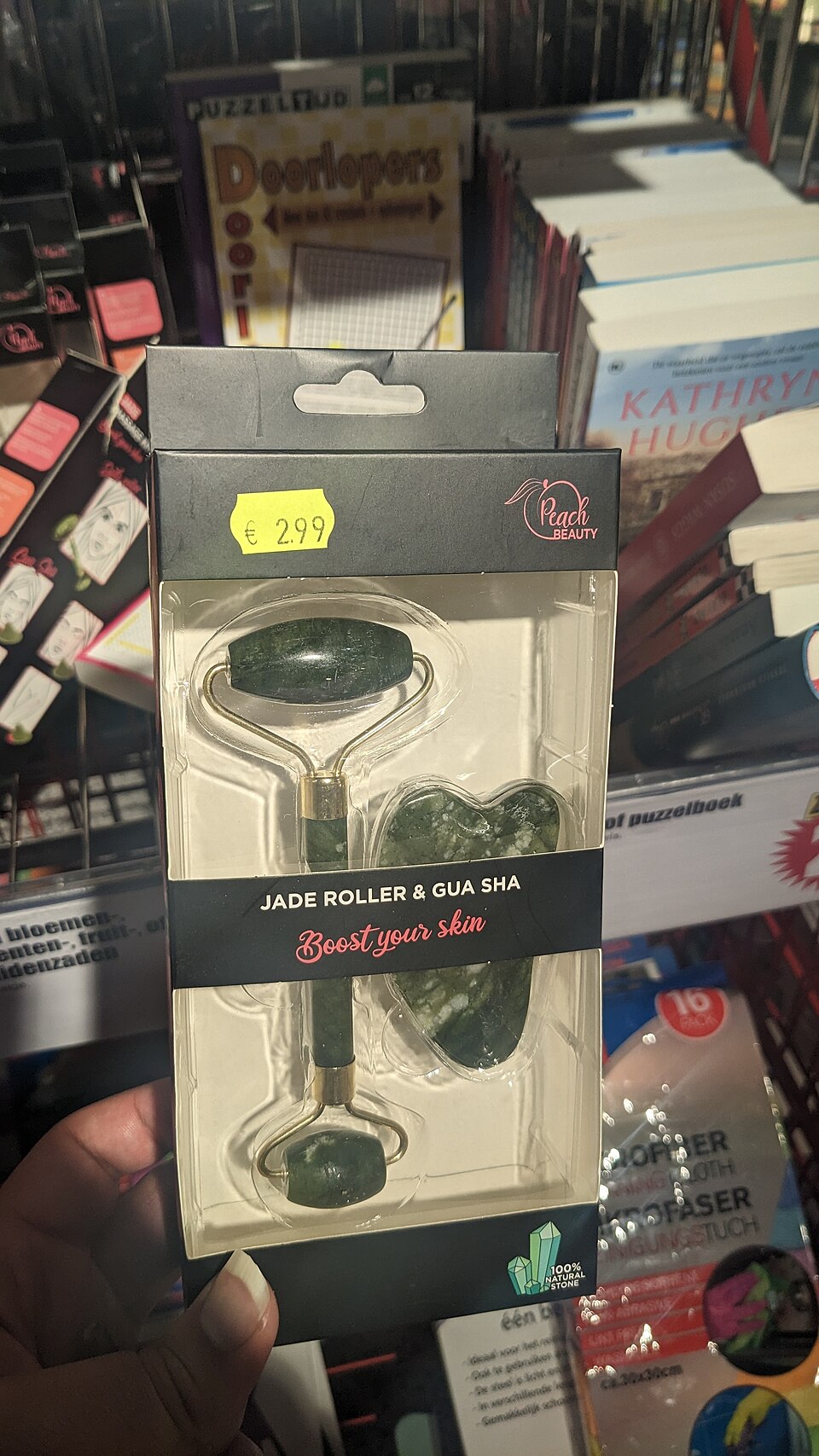 A jade roller and a flat gua sha stone displayed in retail packaging