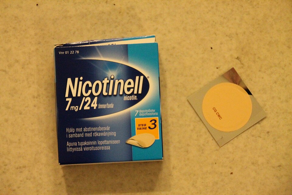 A single square adhesive patch held between finger and thumb