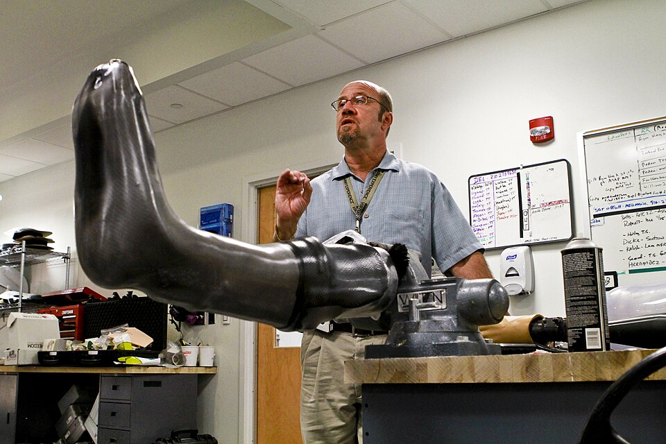 A fitter adjusting the straps of a leg brace on a seated person